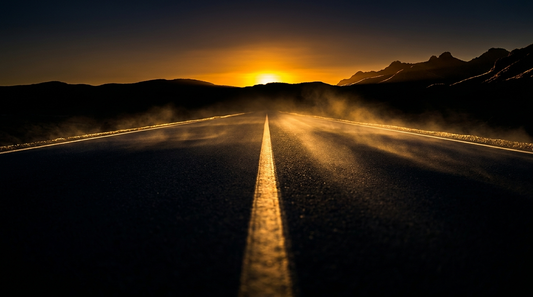 Cinematic dark-and-gold empty open highway at dawn leading toward a molten gold horizon